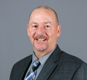 Man wearing dark grey suit and plaid blue tie.