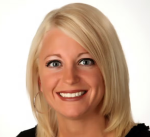 A woman with short blonde hair wearing a black shirt and silver hoop earrings.