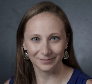 Woman with brown hair wearing a navy blue sleeveless shirt.