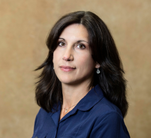 A woman with black hair wearing a navy blue collared blouse.