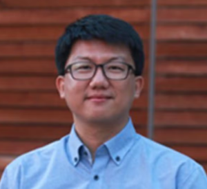 Man with short black hair wearing a light blue collared shirt.