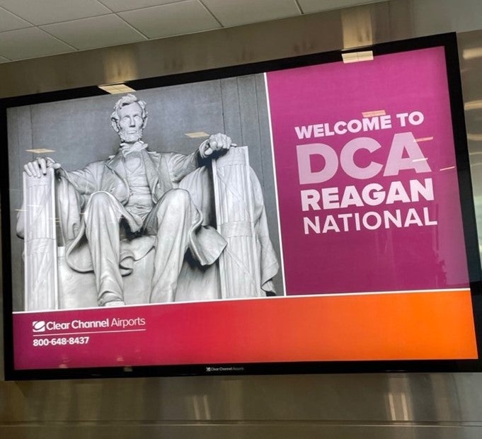 A big screen television shows a statue of Abe Lincoln and a graphic that says, "Welcome to DCA Reagan National"