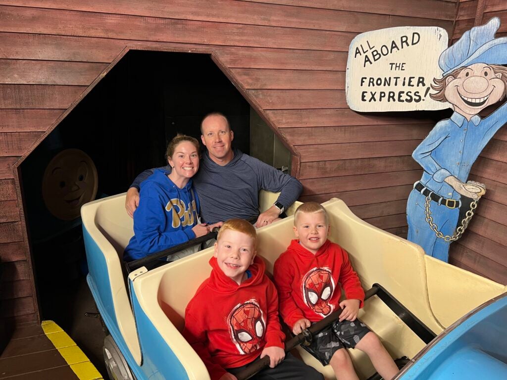 A family of four -- wife, husband and two sons -- sitting in a rollercoaster car.