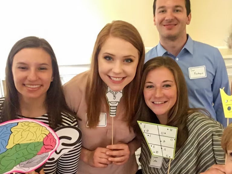 Three women and a man standing together holding graphics and diagrams related to communication science.