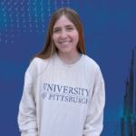 Woman with brown hair wearing a white sweatshirt with "University of Pittsburgh" printed on it.