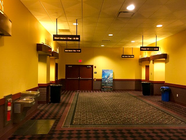 A large hallway of a movie theatre shows the entrances to four movies.