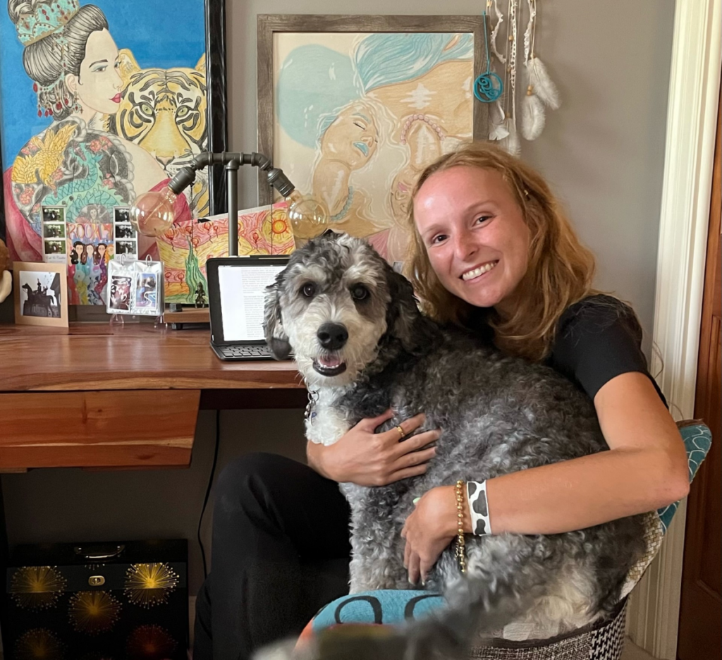 Woman with blonde hair sitting in a chair with a large gray dog in her lap