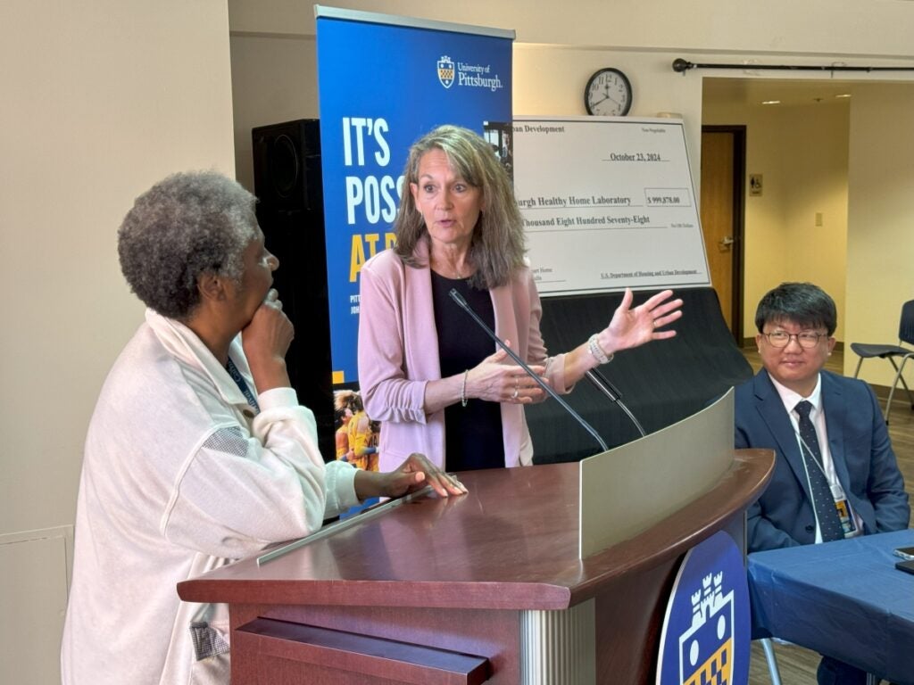 A community member stands at a podium with HHL Director Pam Toto while Health Informatics Assistant Professor Yong Choi listens