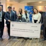 Leaders from the HHL, ACHA and the community stand around a large poster of a check made out to the HHL for their million dollar grant.