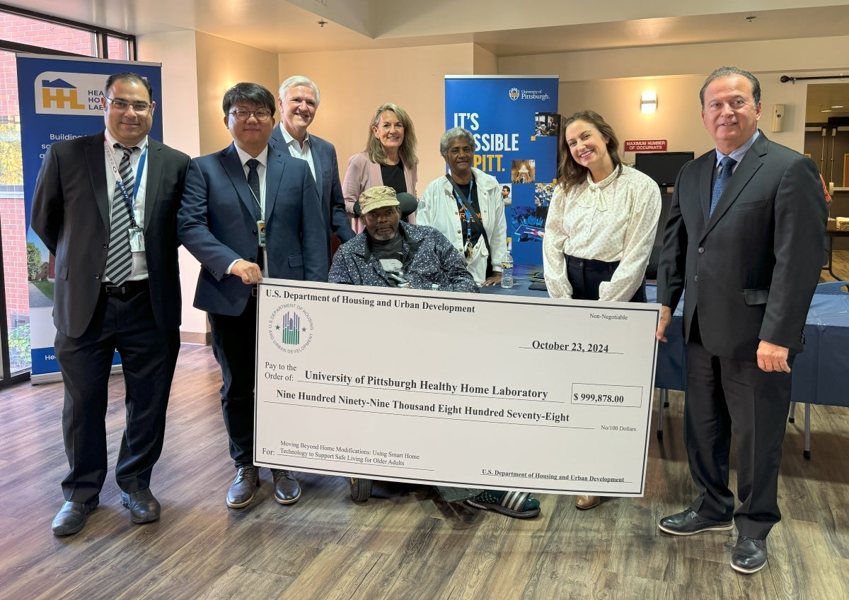 Leaders from the HHL, ACHA and the community stand around a large poster of a check made out to the HHL for their million dollar grant.