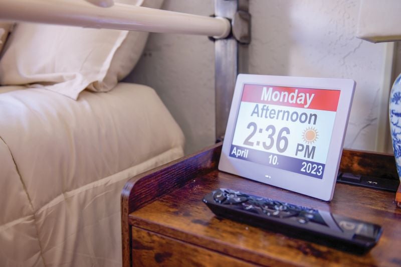 A bed with tan covers with a bedside monitor sitting on the bedside table.