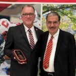 Kevin Conley stands holding an award plaque next to Erik Bitterbaum