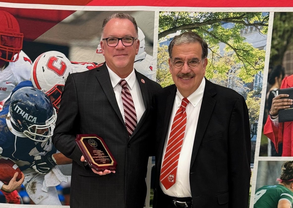 Kevin Conley stands holding an award plaque next to Erik Bitterbaum