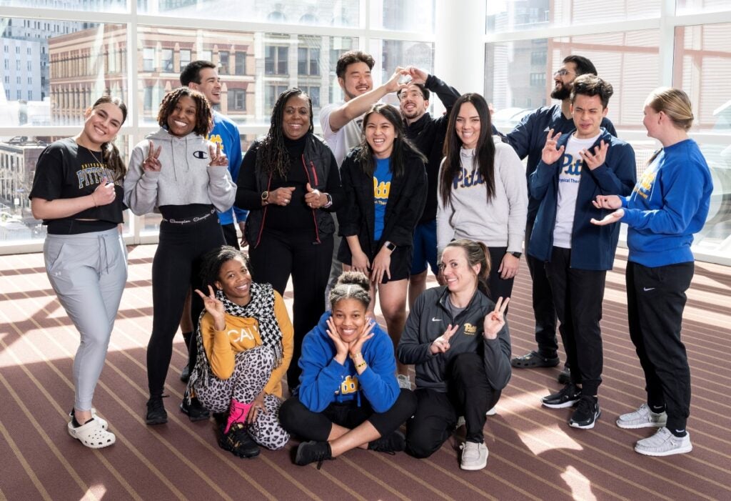 A group of students and their professor make funny poses for the camera