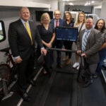 Group of Pitt alumni, faculty and staff standing inside the NMRL mobile research laboratory