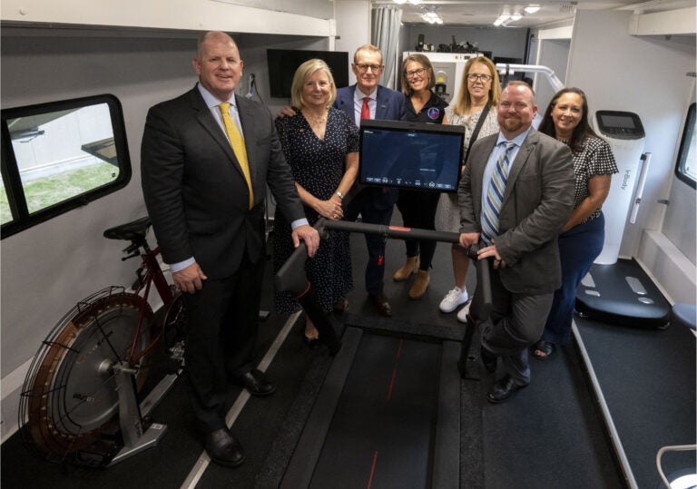 Group of Pitt alumni, faculty and staff standing inside the NMRL mobile research laboratory