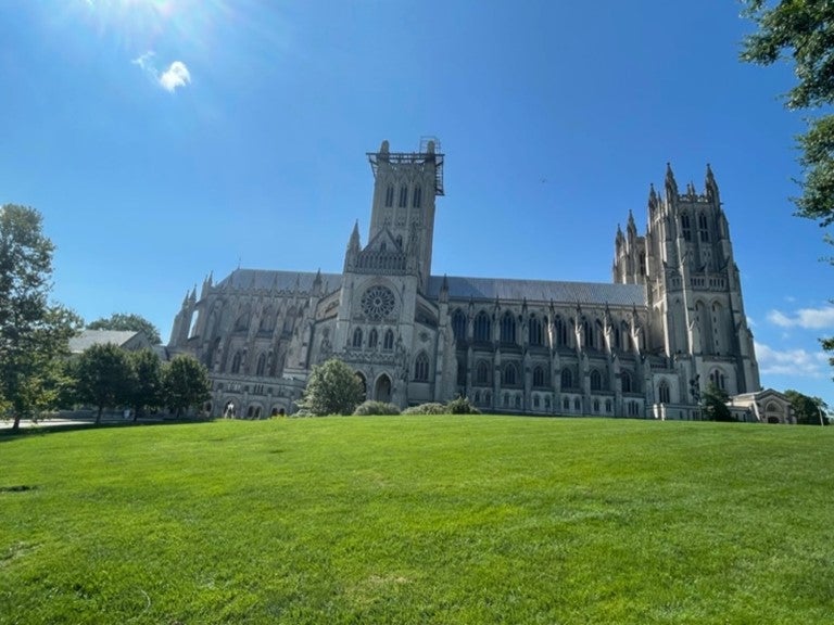 A gothic style church at the top of a bright green hill