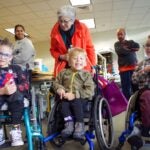 Three young boys in wheelchairs smile at the camera