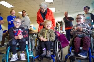 Three young boys in wheelchairs smile at the camera