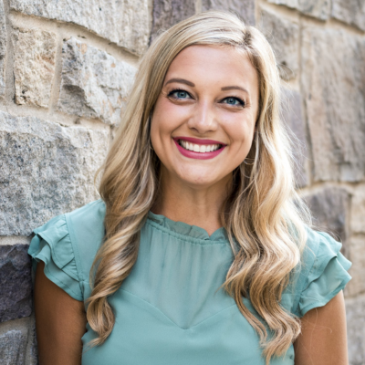 woman with long blonde hair and a pale green blouse smiles at the camera