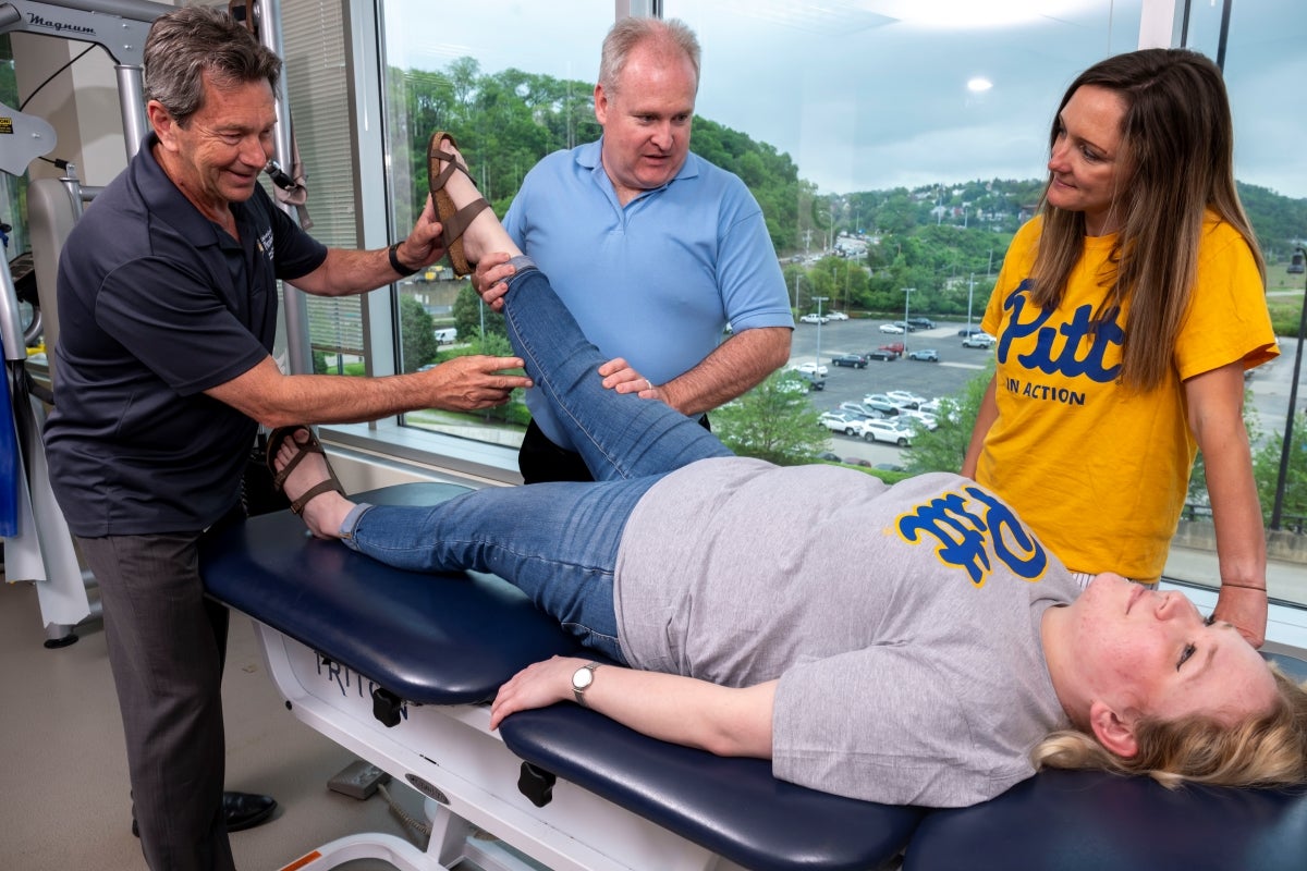 Faculty demonstrate chiropractic maneuvers on patient laying on table while a student watches