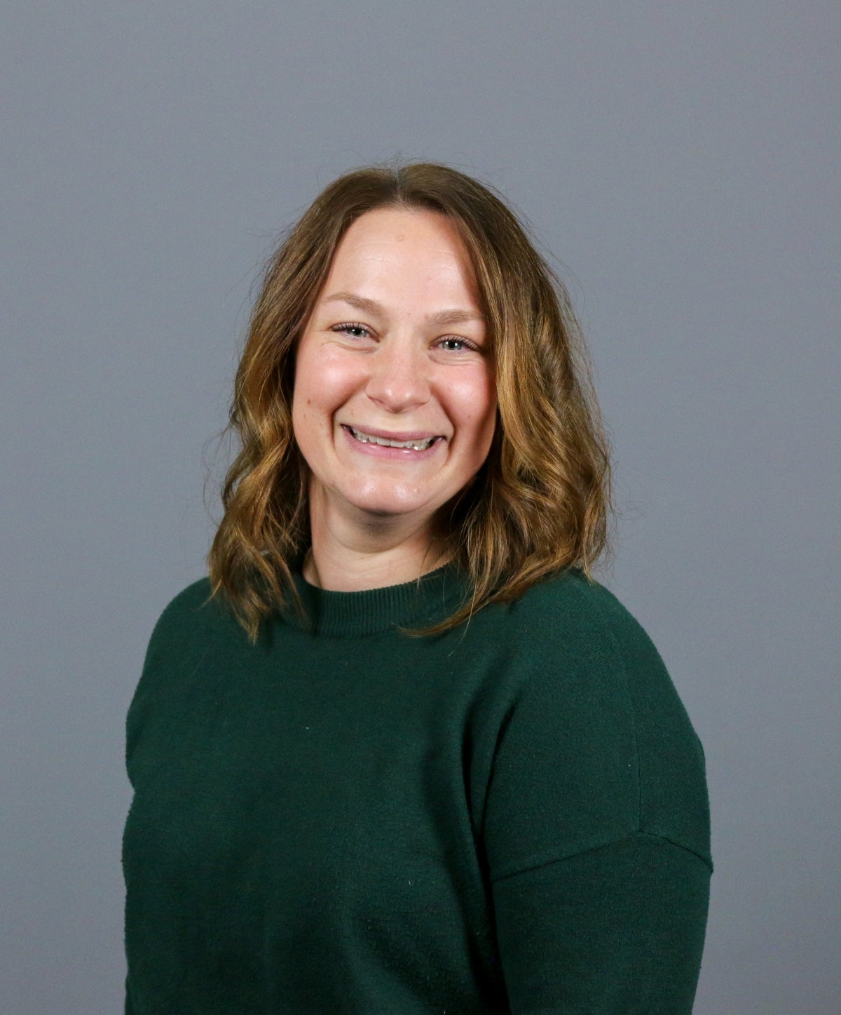 Woman with short brown hair wearing a dark green sweater.