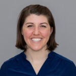 Woman with short brown hair wearing a navy blue blouse.