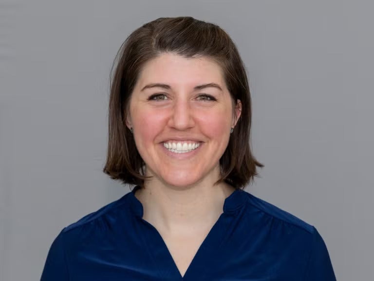 Woman with short brown hair wearing a navy blue blouse.