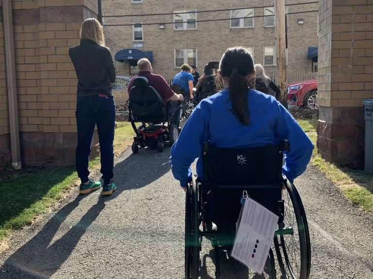 A group of people sitting in wheelchairs outside.