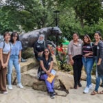 A group of women standing together outside near a panther statue.