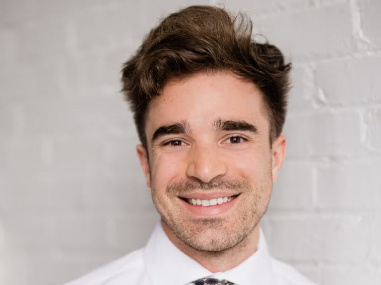 Man with short brown hair wearing a white collared shirt.