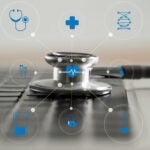 A stethoscope sitting on a keyboard with health icons around it.