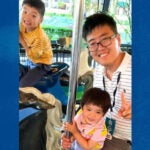 A man and two children sitting on a merry-go-round.