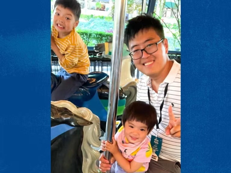 A man and two children sitting on a merry-go-round.